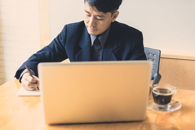 Man using mobile phone while sitting on table