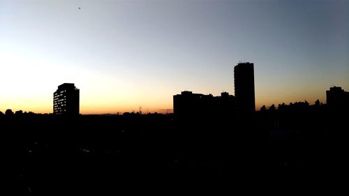 Silhouette buildings against sky during sunset