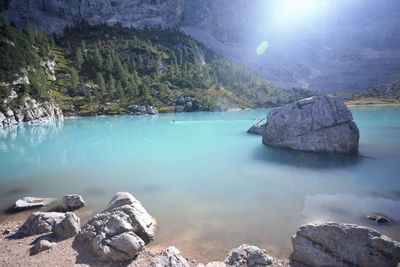 Rocks by lake against sky