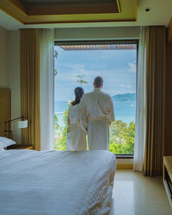 Rear view of woman standing in bed at home