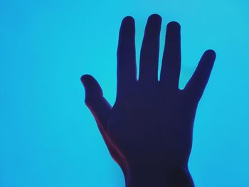 Close-up of cropped hand on blue background