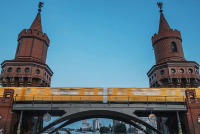 Low angle view of train on oberbaum bridge against clear blue sky in city