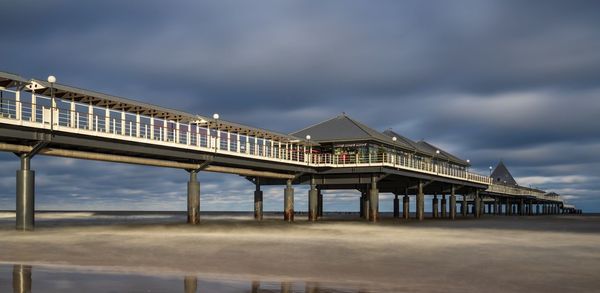 Low angle view of bridge over beach against sky