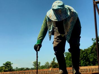 Low angle view of man standing against clear blue sky