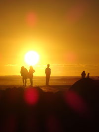 Silhouette people on beach at sunset