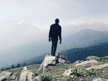 Rear view of man on rocks against mountains