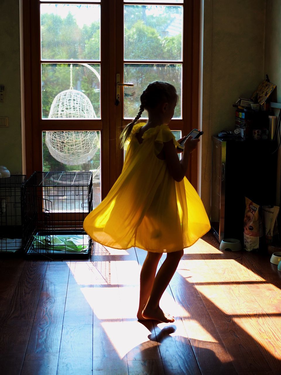 REAR VIEW OF WOMAN STANDING BY WINDOW ON FLOOR