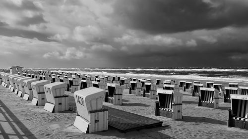 Hooded chairs on beach against sky