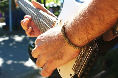 Cropped hand of man playing guitar outdoors