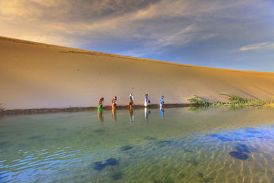 Men fishing in water against sky