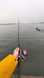 Man fishing in sea against sky