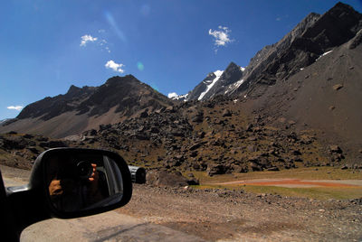 Man photographing car against mountain range