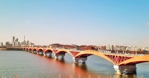 Bridge over river in city against clear sky