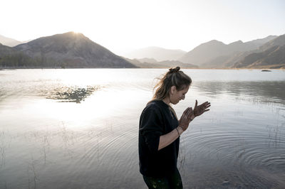 Woman putting mud on hands and face while enjoying outdoors in nature.