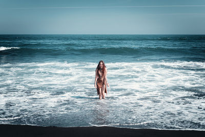 Woman standing on beach against sky