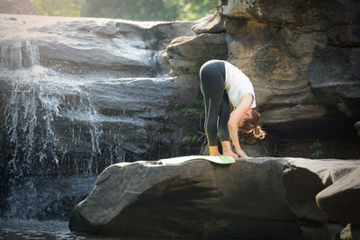 Man standing on rock against waterfall