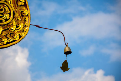 Low angle view of street light against sky. a small bell hangs on the roof.