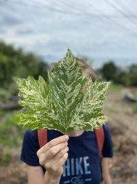 Midsection of person holding plant on field