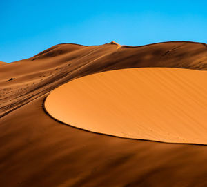 Sand dunes in desert against clear sky