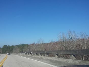 Empty road against clear blue sky