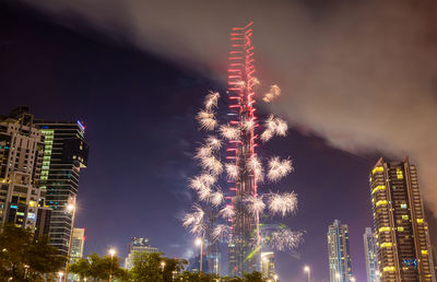 Low angle view of firework display over buildings at night