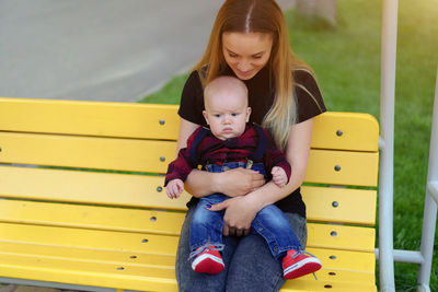 Mother and cute son sitting on bench in park