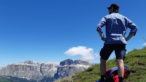 Rear view of man looking at mountain against blue sky