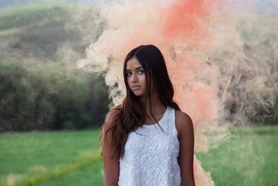 Young woman surrounded by pink smoke