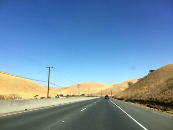 Road by mountain against clear blue sky