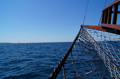 Sailboat on sea against clear blue sky