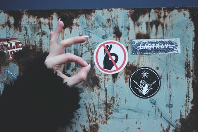 Cropped hand of woman gesturing ok sign by symbol on wall