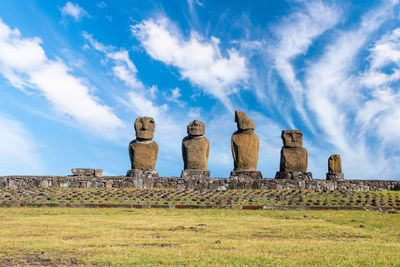 Stone statues on field against sky