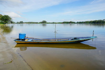Boat moored in lake against sky