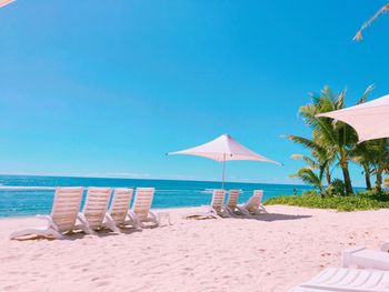 Deck chairs on beach against clear blue sky