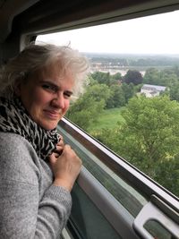 Portrait of smiling woman sitting in vehicle against trees