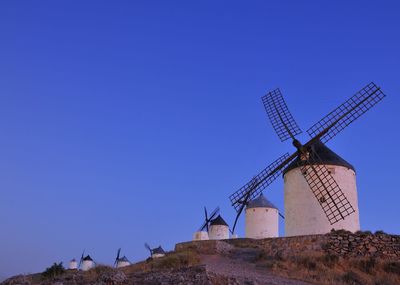 Traditional windmill on landscape against clear blue sky