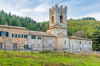 Old building by trees on field against sky