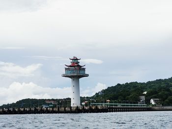 Lighthouse by sea against sky