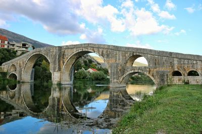 Arch bridge over river against sky