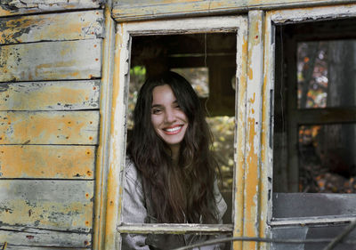 Portrait of smiling young woman against window 