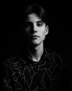 Portrait of teenage boy against black background