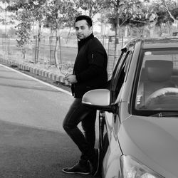 Portrait of young man standing on road in city