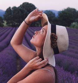 Woman wearing hat looking up while standing outdoors