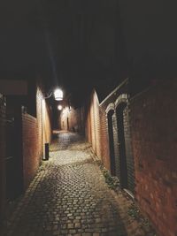 Empty alley amidst buildings at night