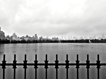 Metal fence by lake against sky