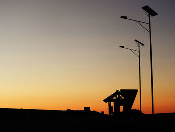 Silhouette street light against orange sky