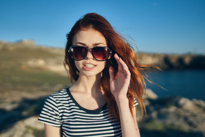 Portrait of young woman wearing sunglasses against sky