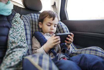 Cute boy using smart phone in car