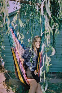 Girl looking away while sitting in hammock in yard