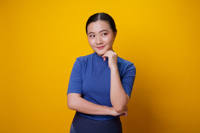 Portrait of a smiling young woman against yellow background